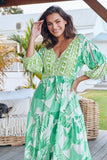 Woman wearing a green and white patterned dress outdoors.
