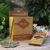 Palo Santo spiritual smudge incense packaging with incense sticks on a wooden surface with plants in the background.