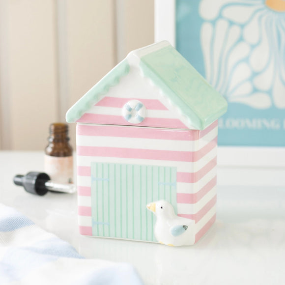 Decorative striped box with a green roof and small bird figurine on a white surface.