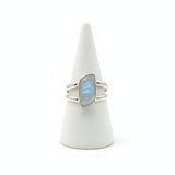 Silver ring with a blue gemstone on a white cone stand