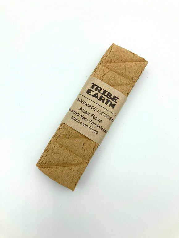 A handcrafted incense plank made from sandalwood and rose, branded by Tribe Earth, packaged in a brown paper sleeve with a label.