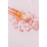 Roll-on bottle with pink crystals on a light pink background