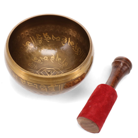 Bronze singing bowl with engraved designs and a wooden mallet on a white background