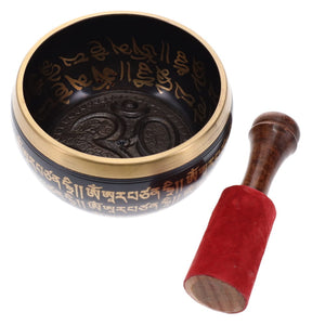 Tibetan singing bowl with engraved designs and wooden striker on a white background