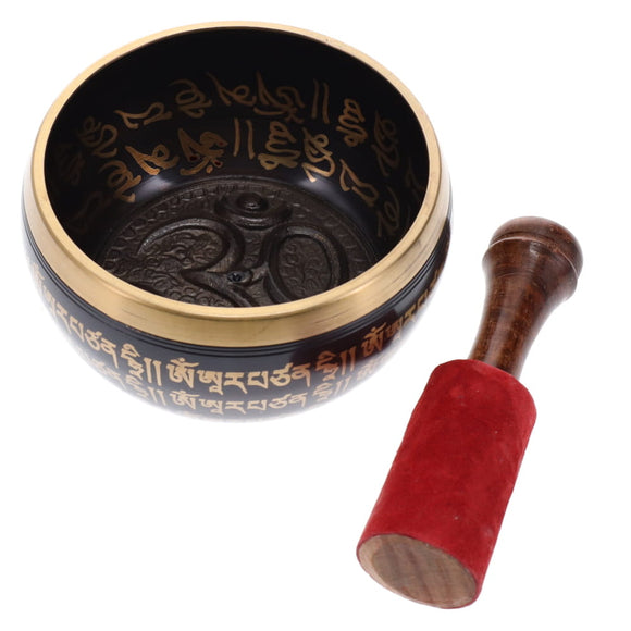 Tibetan singing bowl with engraved designs and wooden striker on a white background