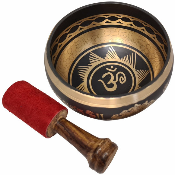Decorative singing bowl with Om symbol and a wooden mallet on a white background