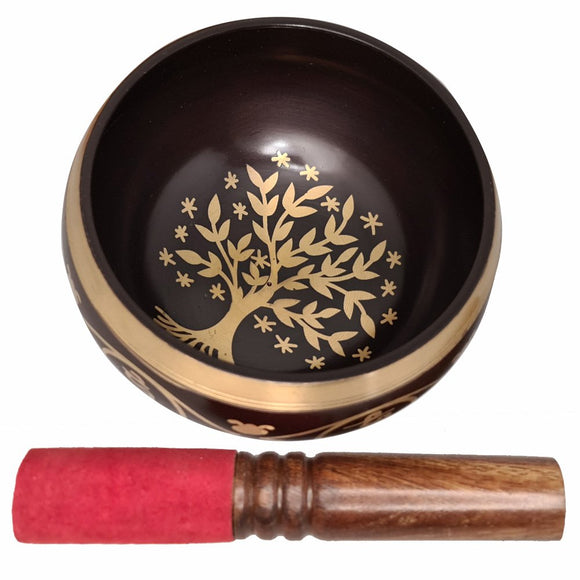 Decorative singing bowl with a tree design and a wooden mallet on a white background