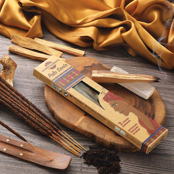 Palo Santo incense sticks with packaging on a wooden surface with yellow fabric in the background