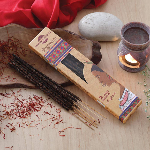 Saffron sticks with packaging on a wooden surface with a candle and red fabric.