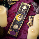 Tarot card packaging with candles and crystals on a purple fabric background