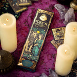 Tarot card box with candles and crystals on a purple fabric background