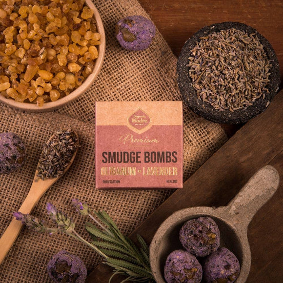Smudge bombs with lavender and a box labeled 'Premium Smudge Bombs' on a wooden surface.