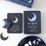 Sodalite crystal, packaging, and decorative items with celestial design on a white surface