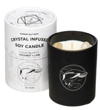 Black candle with whale design next to white packaging labeled 'Crystal Infused Soy Candle'.