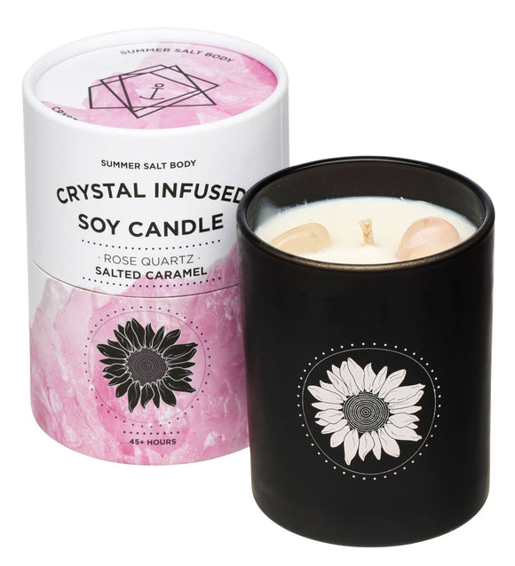 Black candle with sunflower design next to a pink and white candle container on a white background