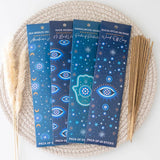 Four packs of incense sticks with blue packaging on a woven mat.