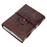 A dark brown embossed leather journal with a decorative circular medallion and a blue stone accent, tied with a matching brown elastic band, shown on a plain white background.