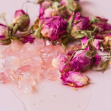 Pink dried flowers and rose petals on a white surface