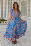 Woman wearing a blue floral dress on a white wooden deck.