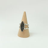 Silver ring with a unique stone design on a wooden display block,