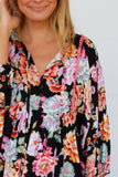 Woman wearing a black floral blouse against a white background