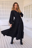 Woman wearing a black dress standing on a wooden deck.