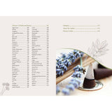 Book pages with a list of herbs and a small illustration of lavender cones on a wooden surface.