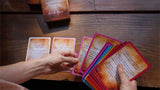 Hands holding tarot cards on a wooden surface