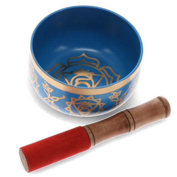 Blue singing bowl with gold patterns and a wooden mallet on a white background