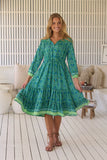 Woman wearing a green patterned dress in a living room setting