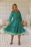 Woman wearing a green patterned dress in a modern indoor setting
