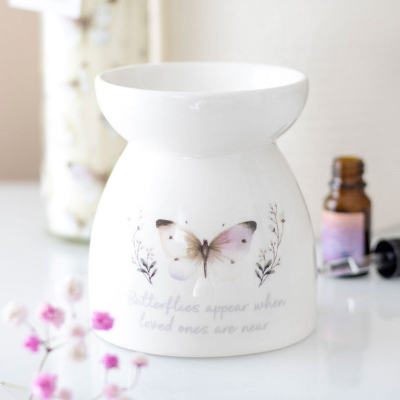 White ceramic warmer with butterfly design and text on a light background