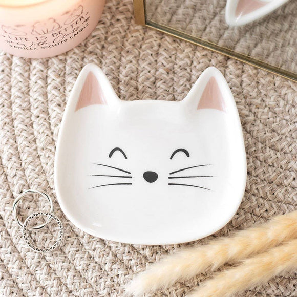 White ceramic dish shaped like a cat's face on a textured surface