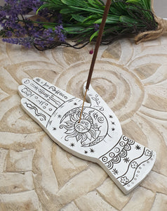Decorative hand-shaped incense holder with sun design on a stone surface with lavender.