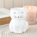 White cat-shaped night light on a textured surface with a candle in the background.