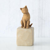 Brown cat figurine on a beige stone base against a white background