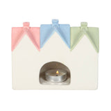 Pastel-colored house-shaped candle holder with a lit tealight on a white background