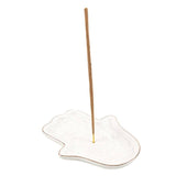 Incense stick on a white ceramic holder with a plain background