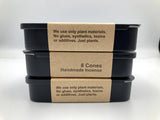 Stack of black containers with brown labels on a white background