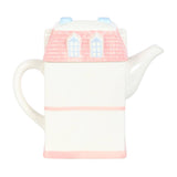Teapot shaped like a house with a pink roof and base on a white background