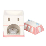 Ceramic tea light holder with a small house design on a white background