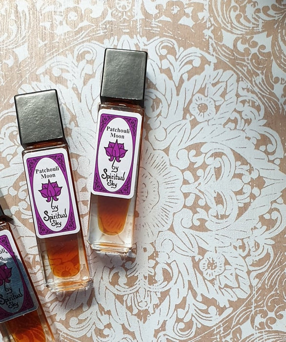 Bottle of Spiritual Sky Perfume Oil with a patchouli fragrance, placed on a surface with a floral patterned background.