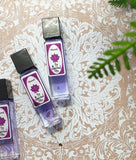 Two bottles of Spiritual Sky Perfume Oil with the label 'Shanti' on a white background with a floral pattern in the background.